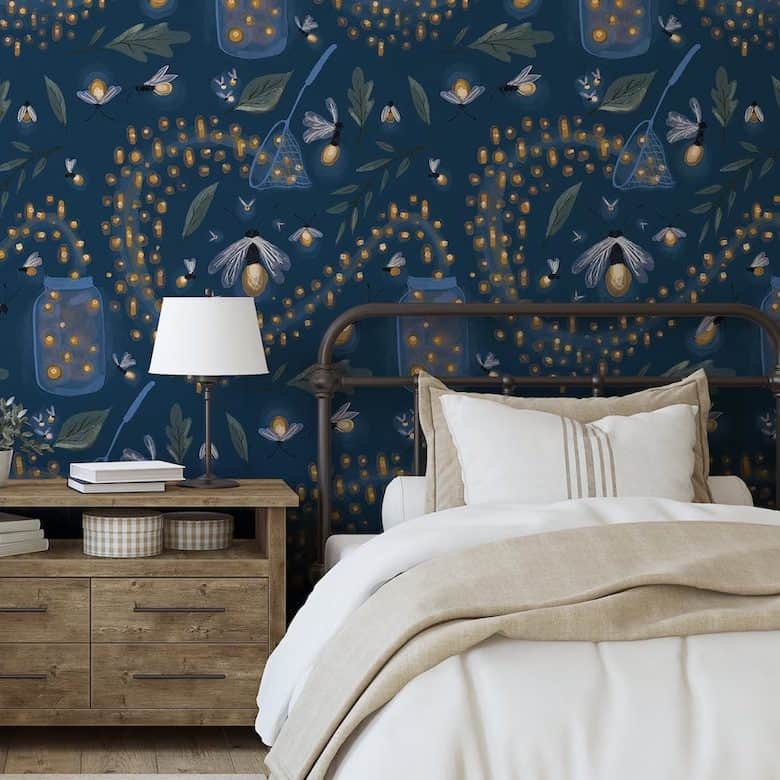 Cozy bedroom with beige bedding, rustic nightstand, and dark blue firefly-themed wallpaper