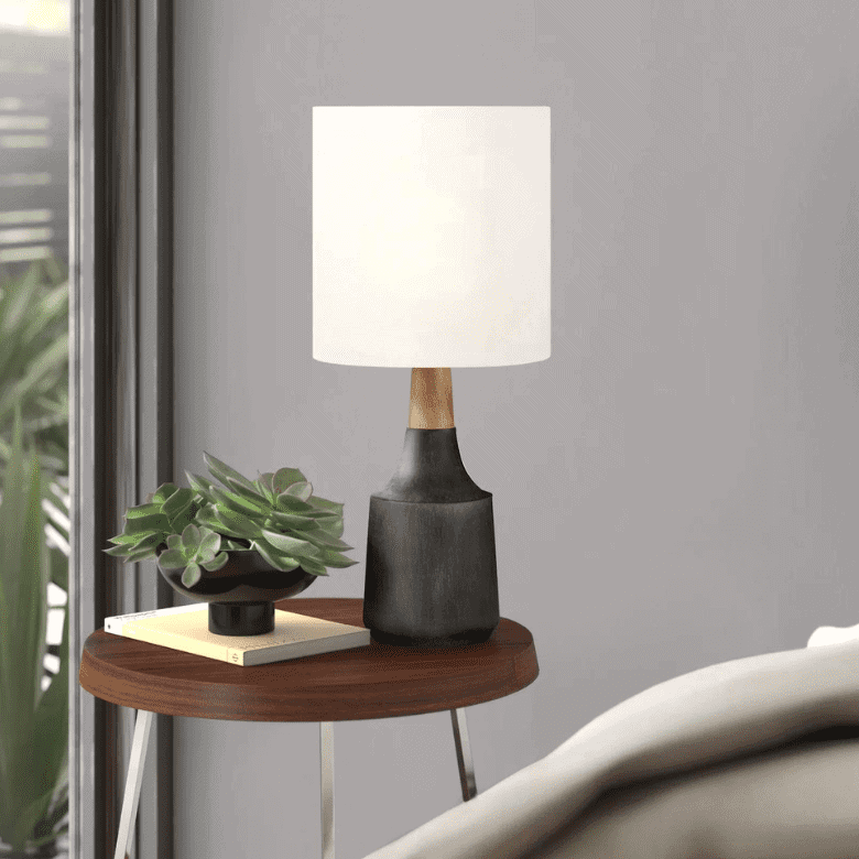 Table lamp with white shade on wood side table
