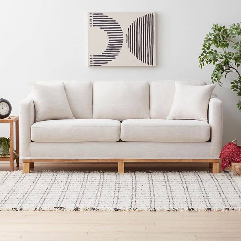 Minimalist living room with light beige sofa, abstract wall art, and checkered textured rug