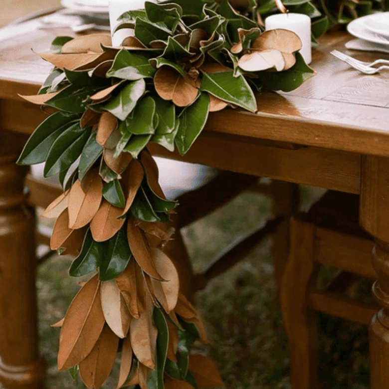 Magnolia leaf garland centerpiece draping over rustic wooden table