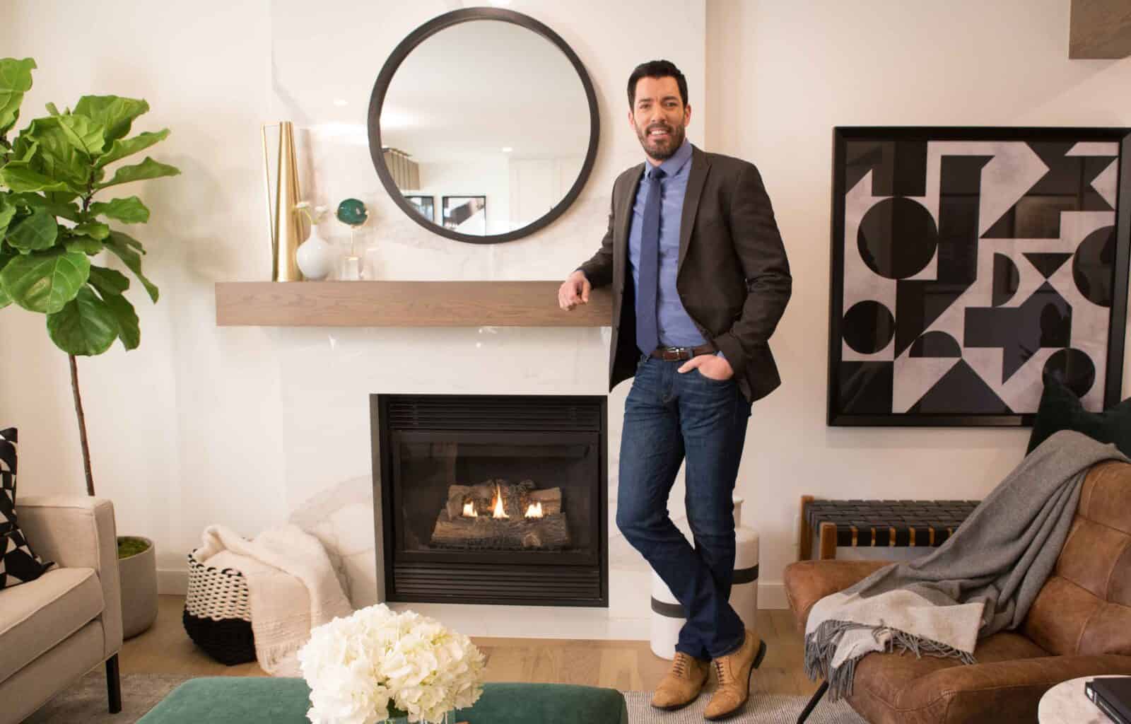 Stylish living room with modern fireplace, round mirror, geometric art, and Drew standing by the mantel