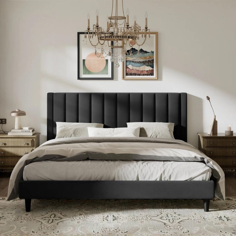 Bedroom with a black upholstered bed, neutral bedding, a crystal chandelier, and framed artwork