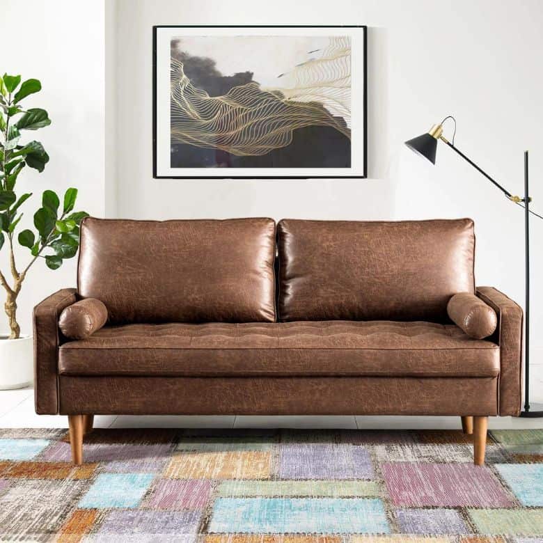 Stylish brown leather sofa with bolster pillows, a colorful patchwork rug, and modern wall art above