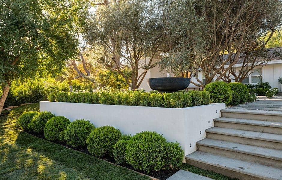 Landscaped garden with tiered greenery, a decorative planter, and stone steps