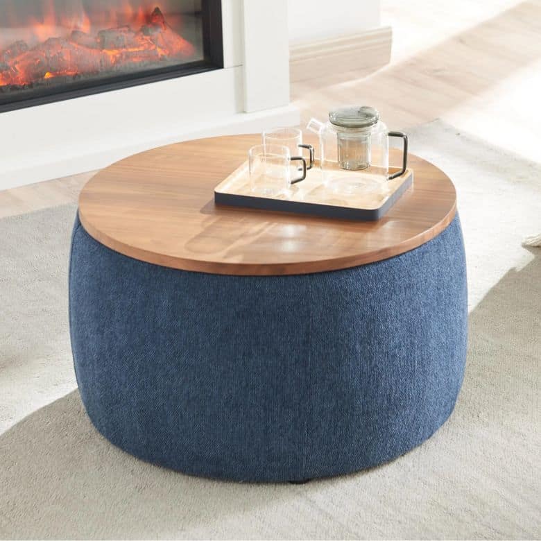 Round ottoman coffee table with a wooden top and blue fabric base, holding a tea set on a tray