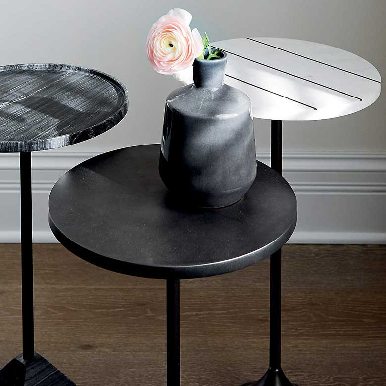 Three modern side tables with a black and white design, featuring a small black vase with a flower