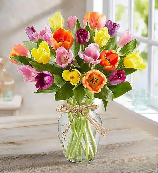 Mixed tulip bouquet in a clear glass vase tied with twine