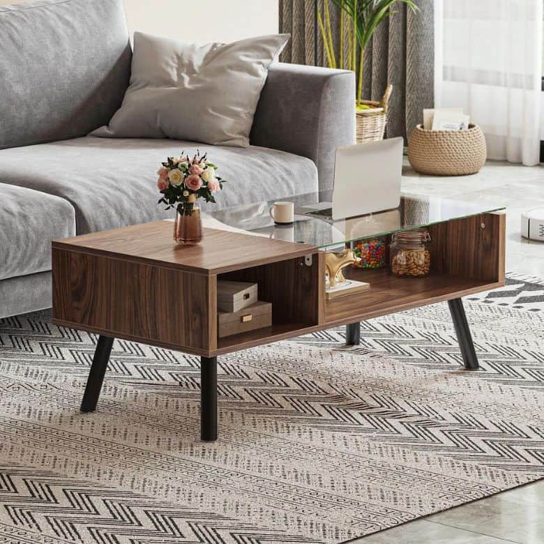 Living room with a gray sofa, wooden coffee table with a glass top, flowers, and colorful candies on the table