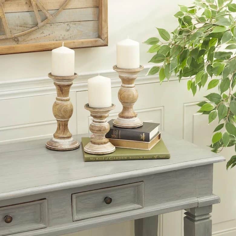 Rustic console table with wooden candle holders, stacked books, and greenery in cozy farmhouse decor
