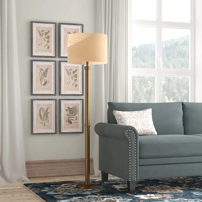Living room with brass floor lamp, blue sofa, and botanical wall art