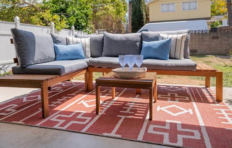 Wooden sectional sofa with gray cushions and blue throw pillows, together with a small coffee table