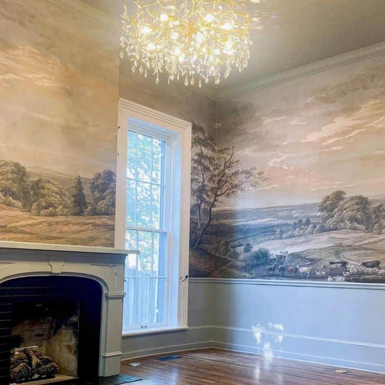 Room with a fireplace, large window, landscape mural walls, and a crystal chandelier