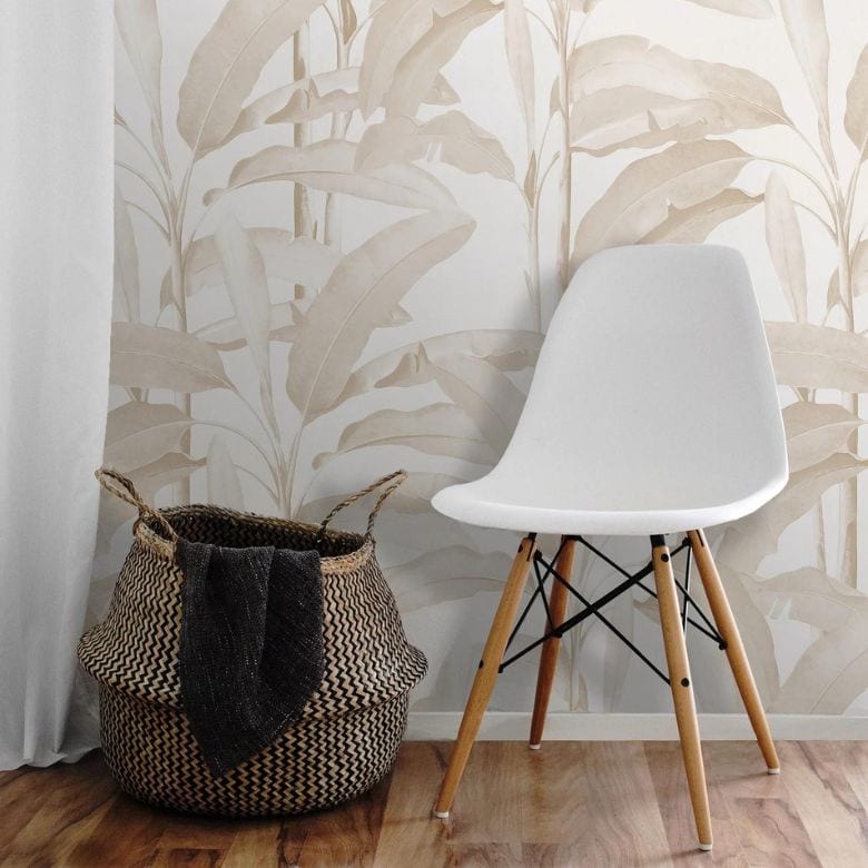 Minimalist corner with a modern white chair, woven basket, and tropical wallpaper