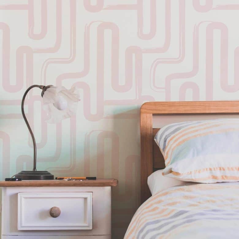 Bedroom scene with a wooden bed frame, patterned bedding, and a nightstand holding a decorative lamp