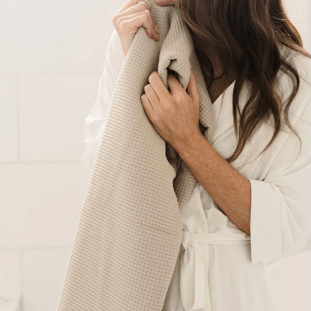 woman holding a beige waffle bath towel