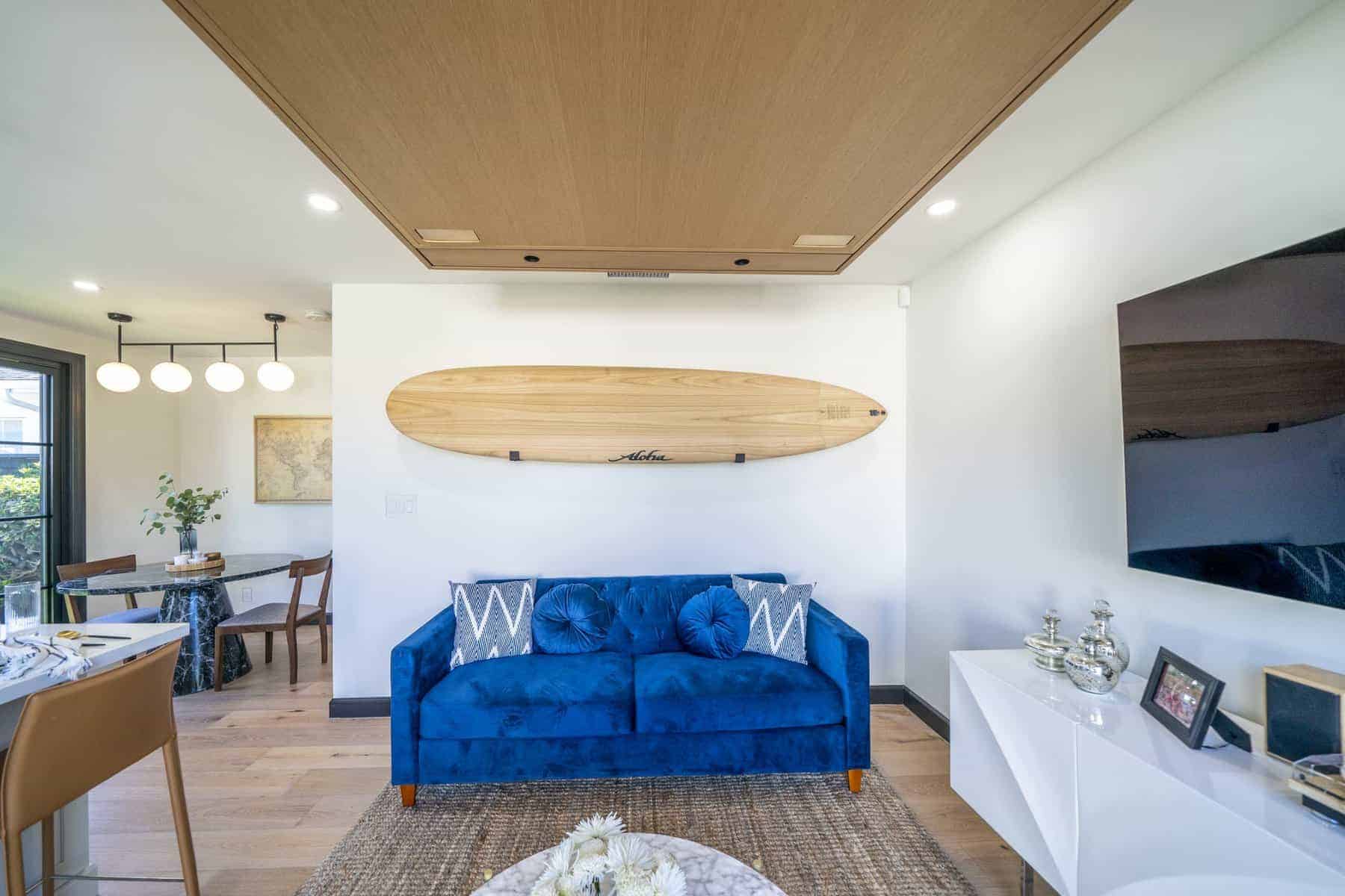 Cozy living area with blue velvet sofa, surfboard wall decor, and natural wood accents