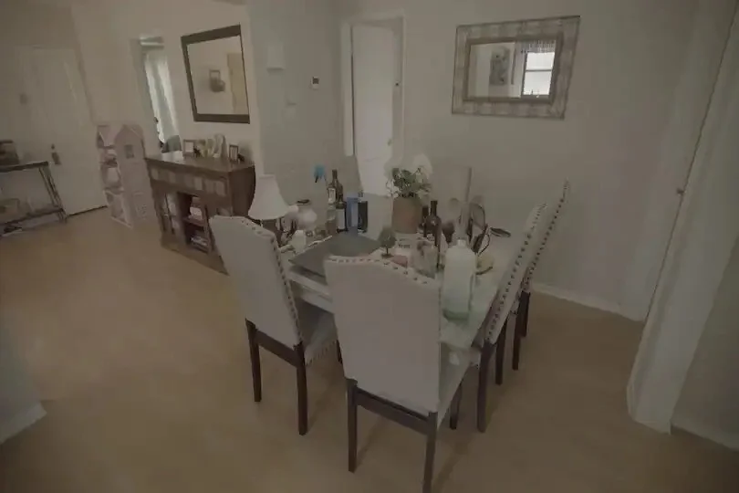Dining room with light wood floors, upholstered chairs, cluttered table, and wall mirror