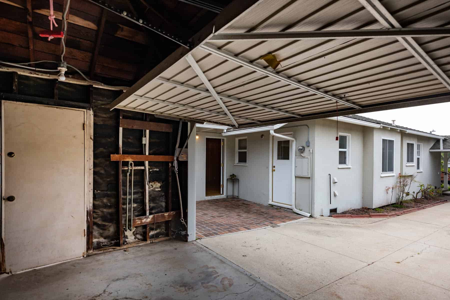 Open garage view facing white house with brick entry and driveway
