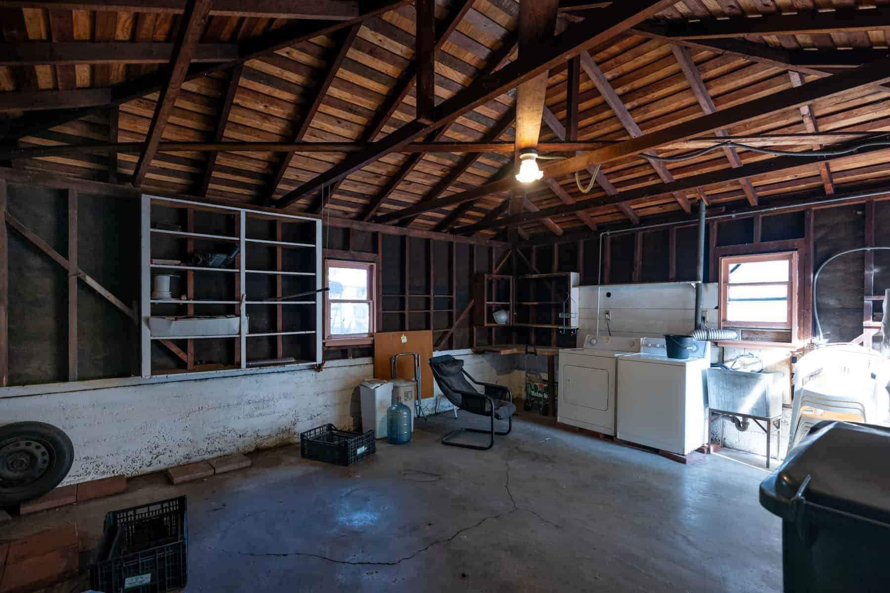 Garage laundry room with exposed beams, utility sink, and washer-dryer setup