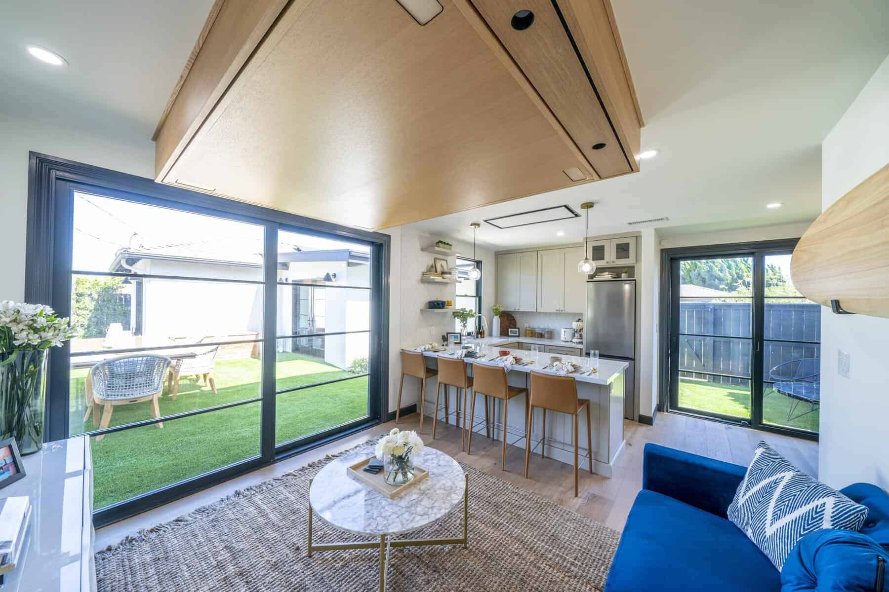 Open-concept kitchen and living area with large sliding glass doors, island seating, and blue sofa
