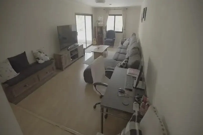 Living room with a sectional sofa, TV, desk setup, and natural light from large windows