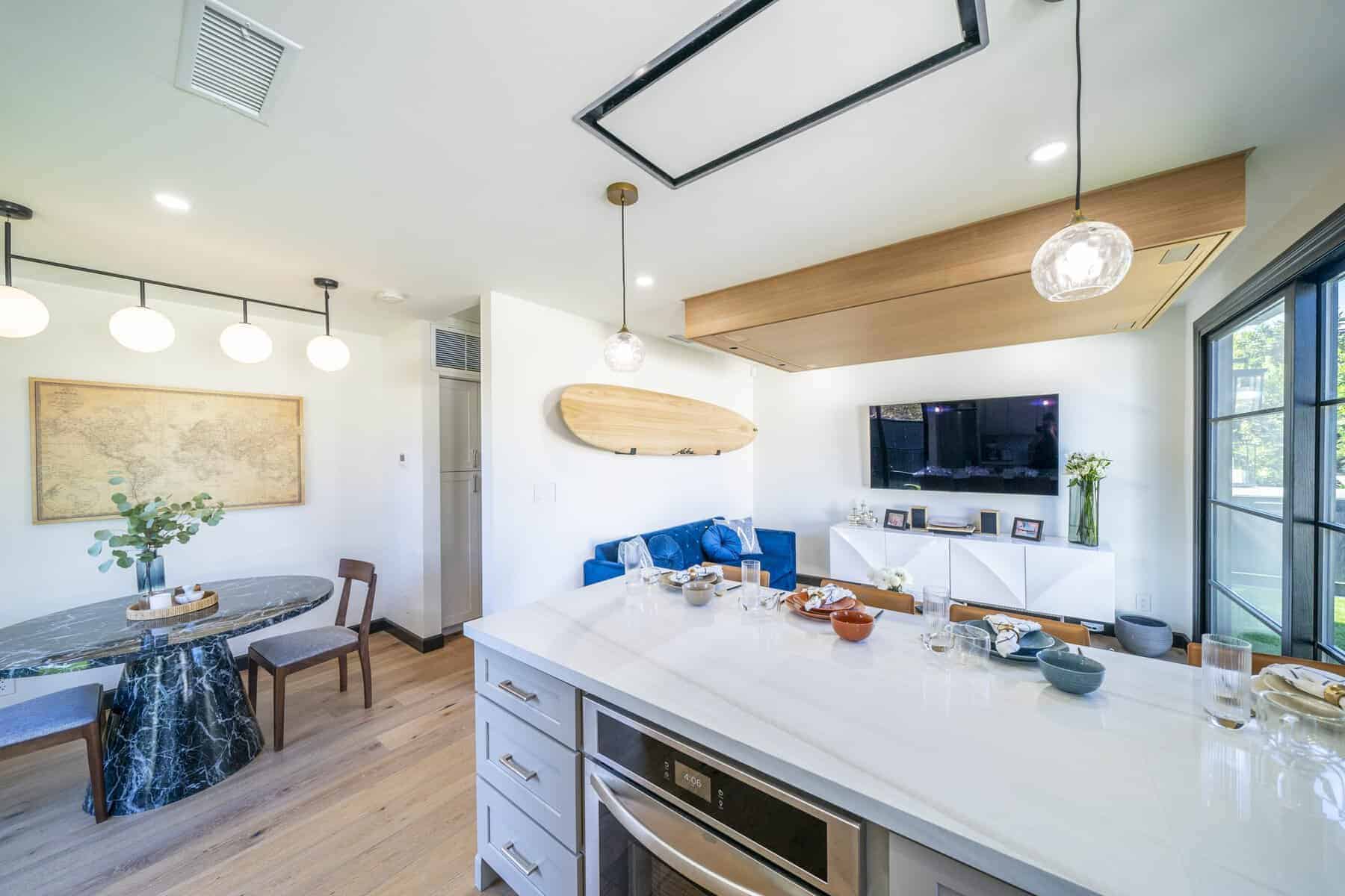 Modern living space with island, marble table, and surfboard décor