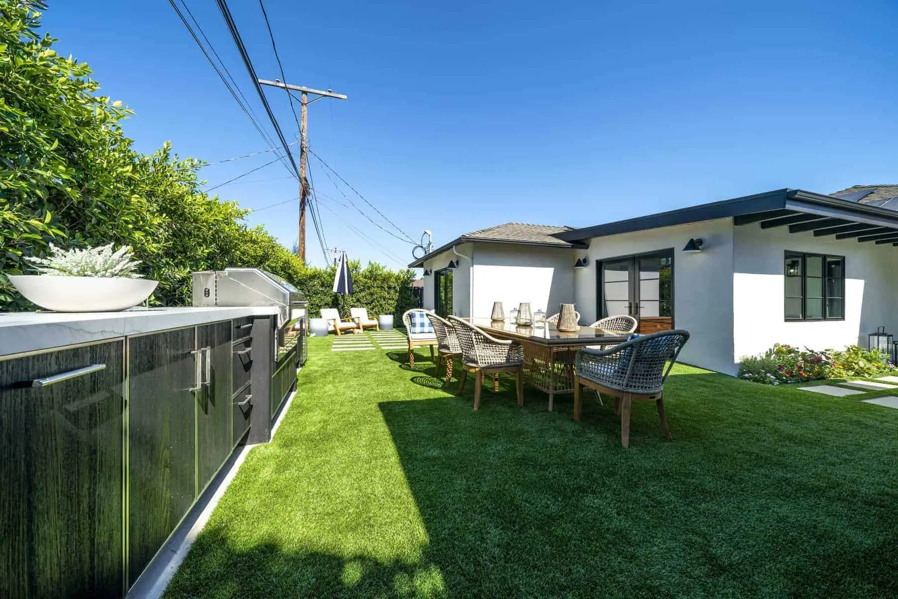 Outdoor dining area with a table, chairs, BBQ grill, and greenery