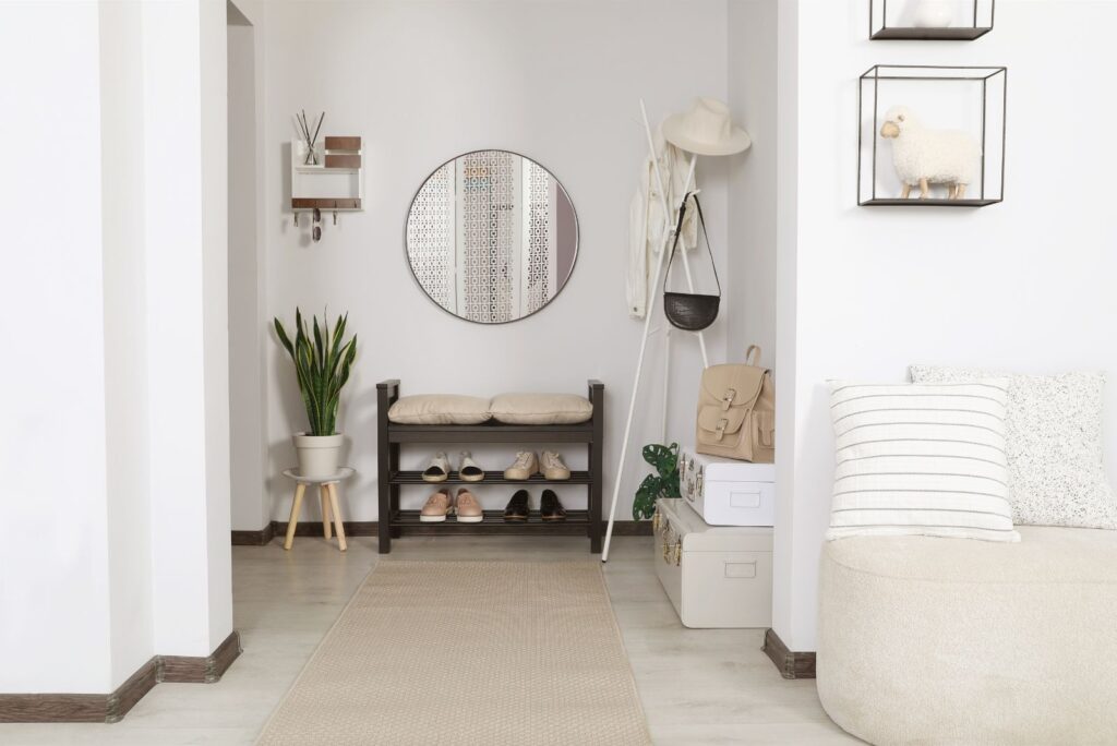 entryway with round wall mirror, shoe bench, and hanging storage