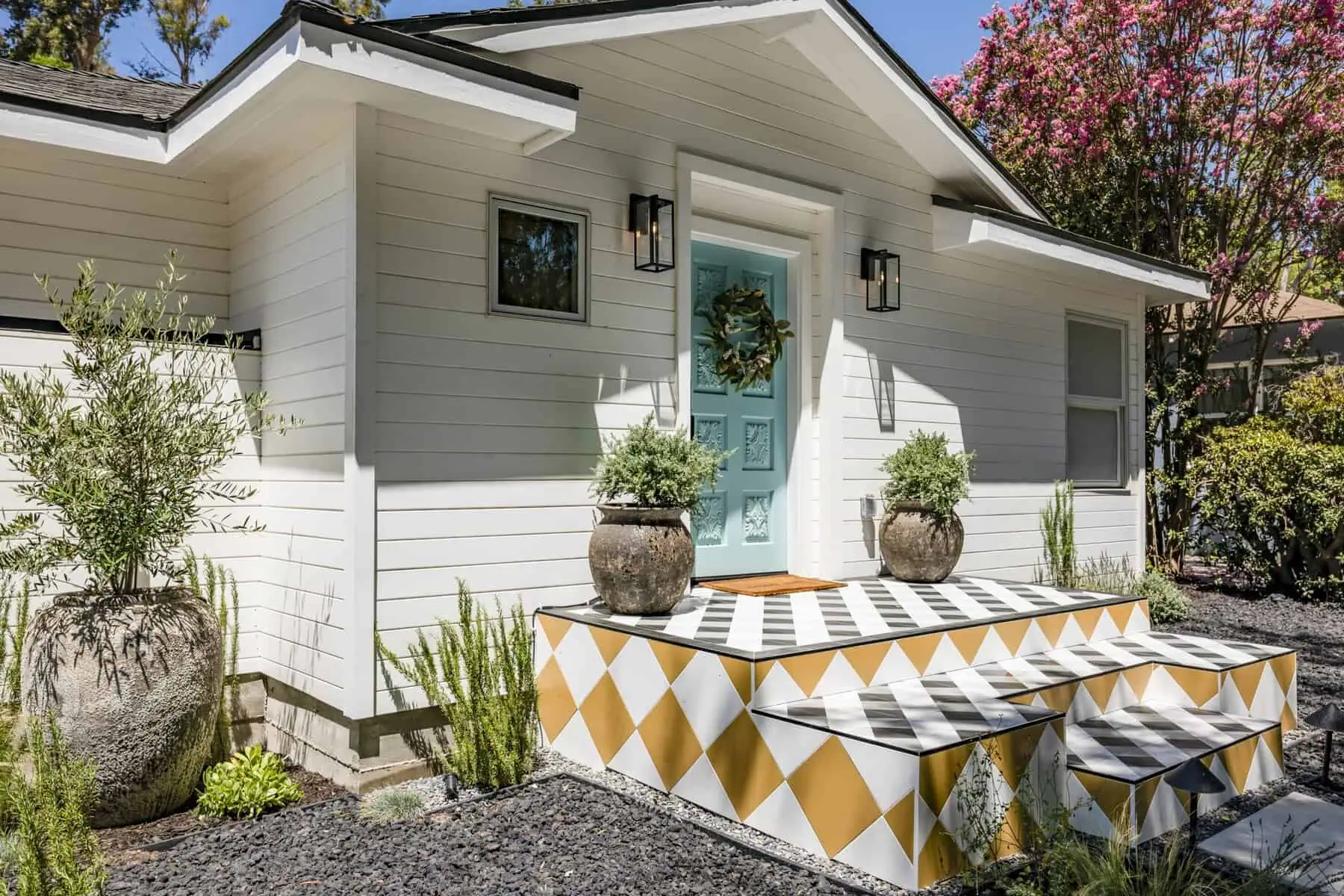 House entrance with a turquoise door, geometric steps, and potted plants