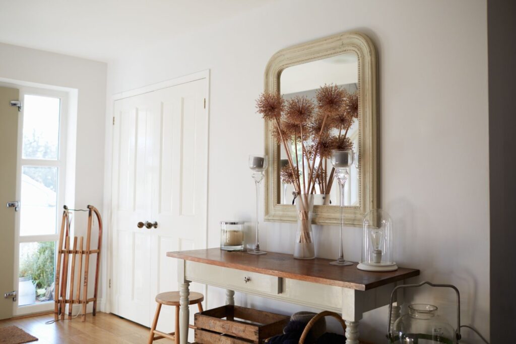 entryway table with vintage arched wall mirror and flower vase