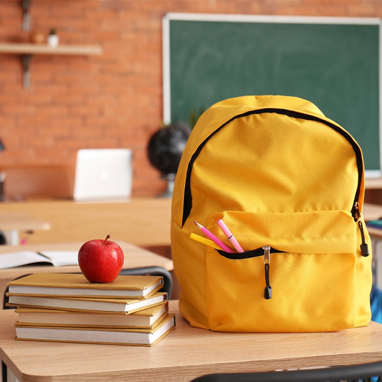 school backpack on a desk with a teacher's apple