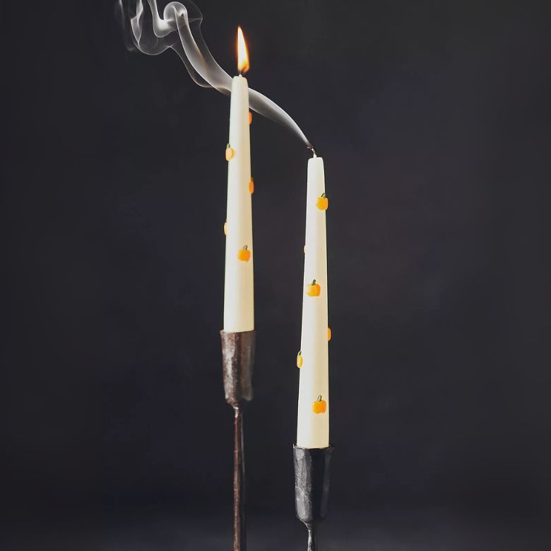 white taper candles with small pumpkins all over