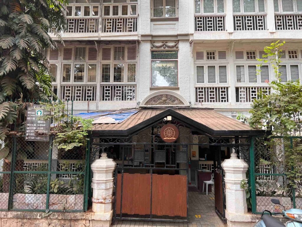 Historic building entrance with gated fence and lush greenery.