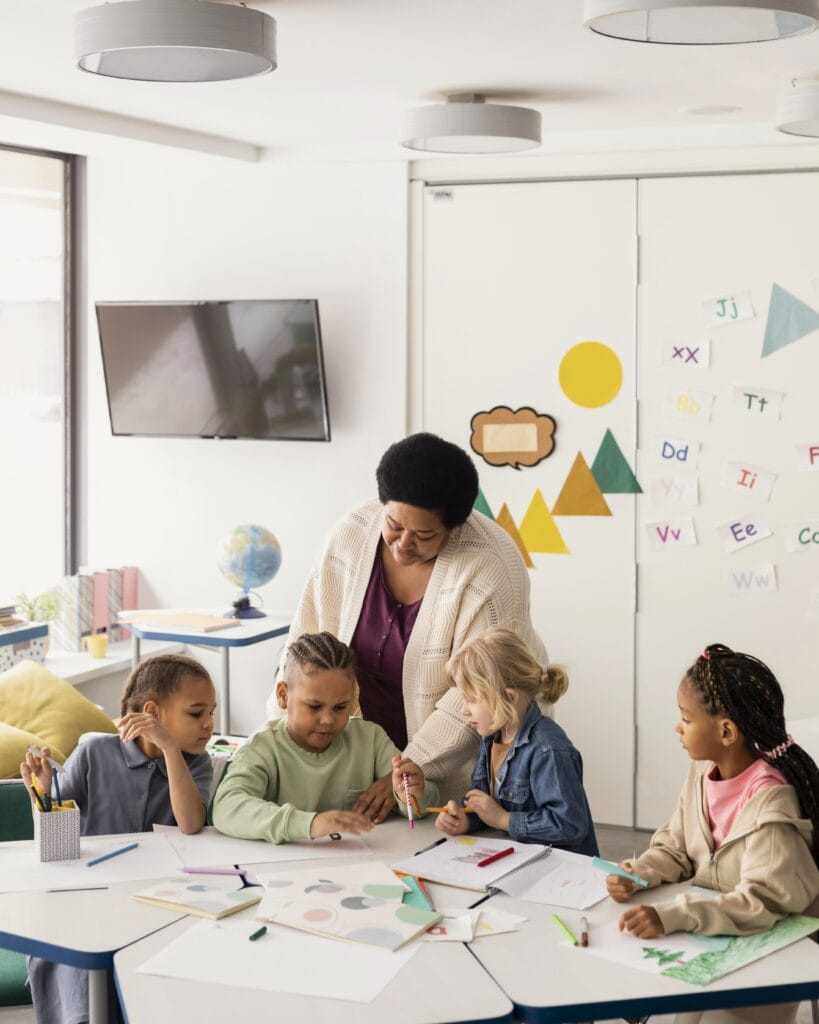 Docente en preescolar guiando a niños en actividades de aprendizaje activo, promoviendo un entorno de inmersión en inglés.