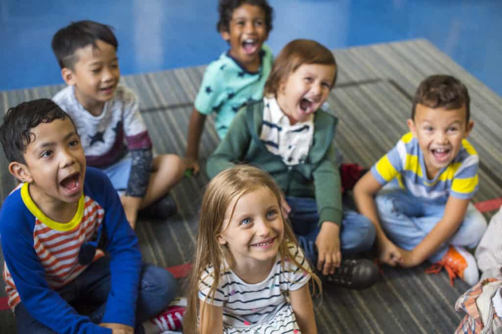Docente en preescolar guiando a niños en actividades de aprendizaje activo, promoviendo un entorno de inmersión en inglés.