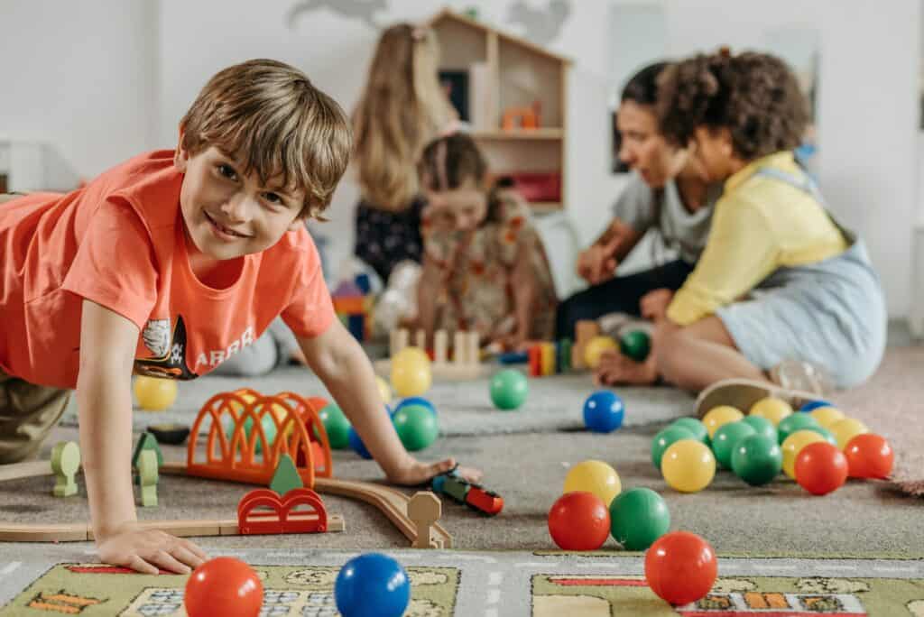Niños pequeños jugando con bloques y pelotas en un entorno preescolar, fomentando el aprendizaje a través del juego