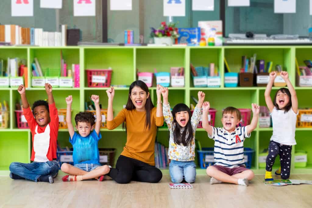 Docente en preescolar guiando a niños en actividades de aprendizaje activo, promoviendo un entorno de inmersión en inglés.