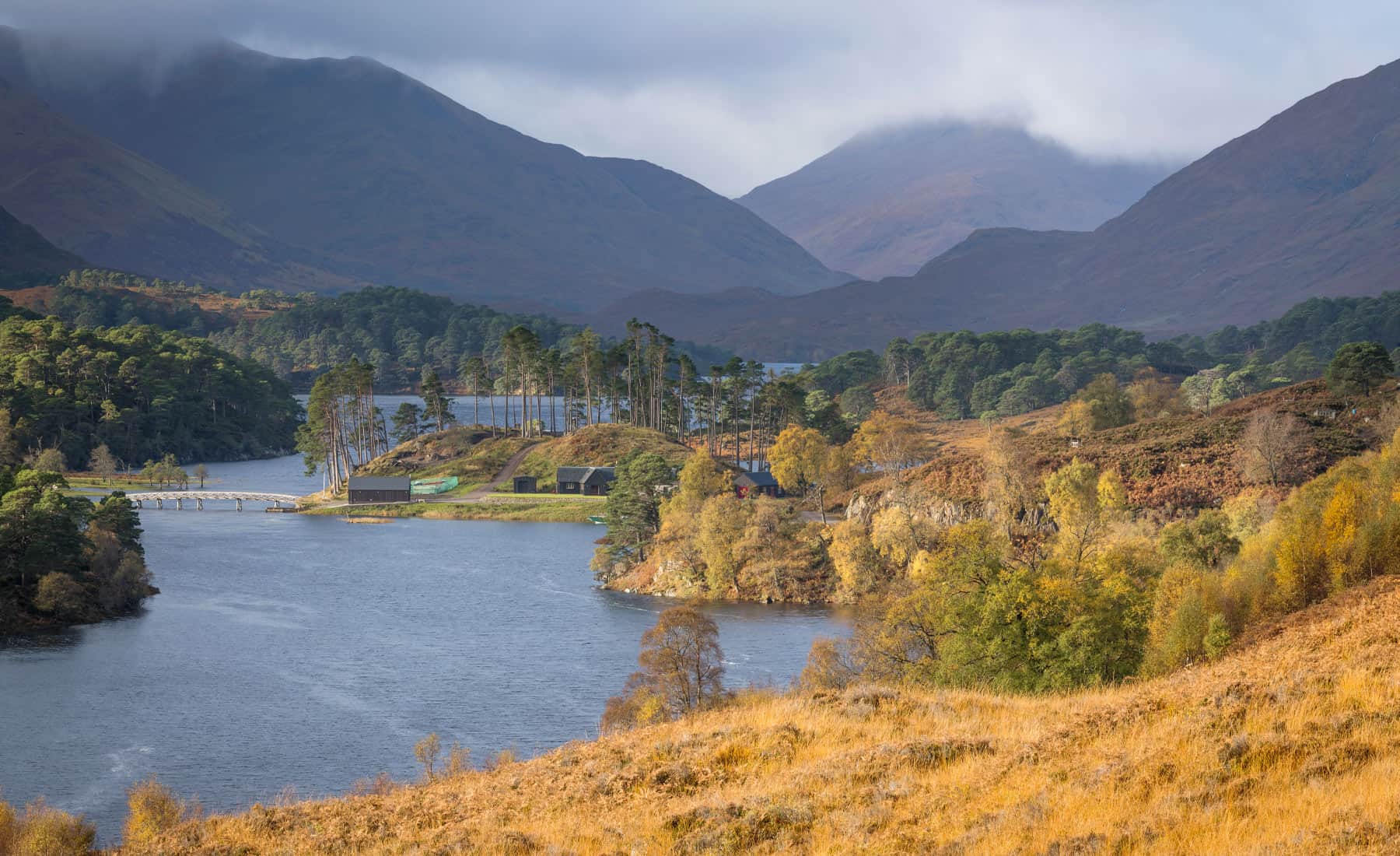 Historic Erchless Castle estate on scenic Highland Loch with mountains and fall foliage.