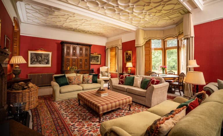 Elegant sitting room at Erchless Castle Estate with traditional furnishings and rich red walls.