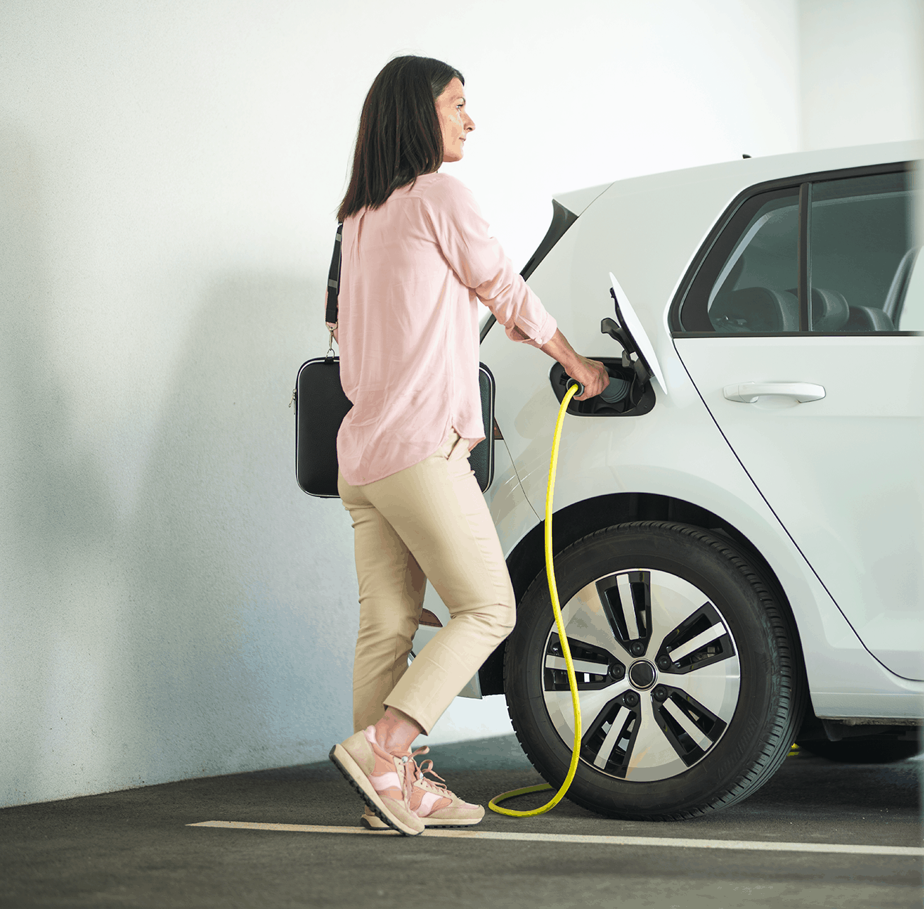 EV charging station with a woman plugging in her electric vehicle.