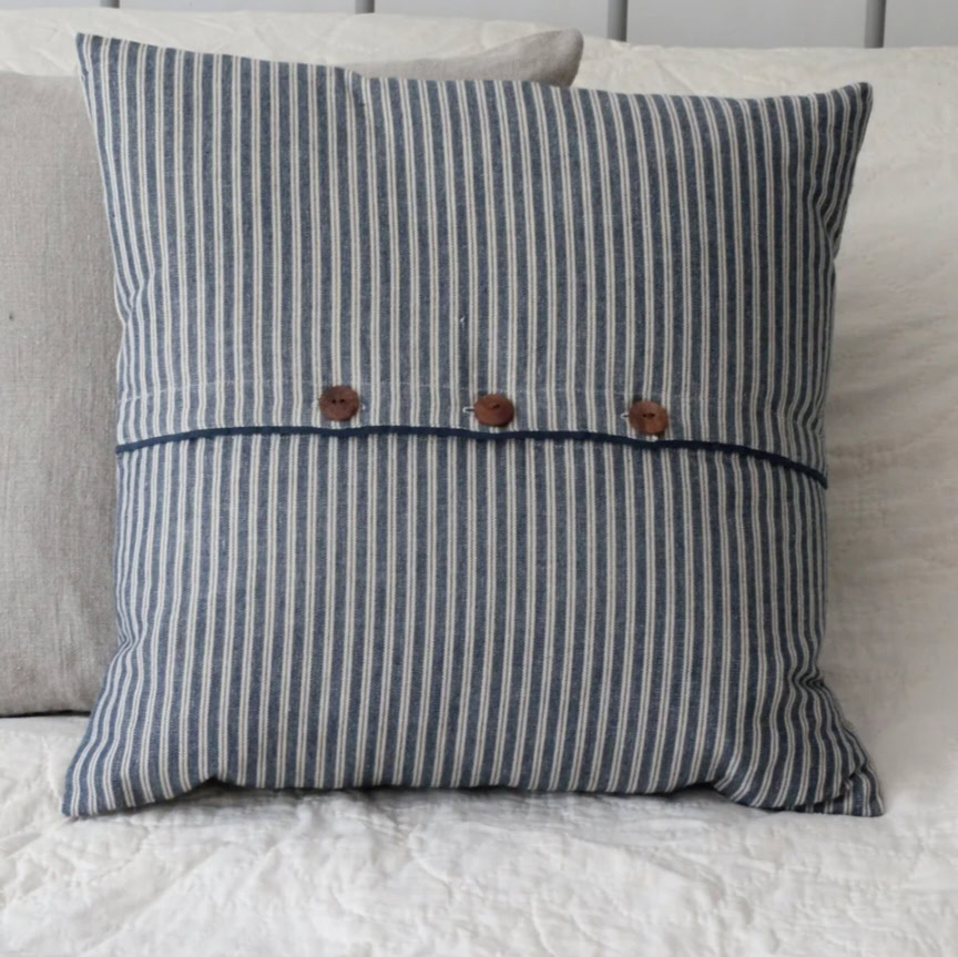Soft striped blue and white cushion with wooden button details, perfect for adding a touch of classic charm to your home decor. Crafted from high-quality fabric by Fabric & Finery UK.