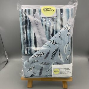 Vibrant fabric & finery gift set featuring patterned textiles with zippers, ideal for sewing, quilting, or crafting projects, displayed on a small wooden stand for presentation.