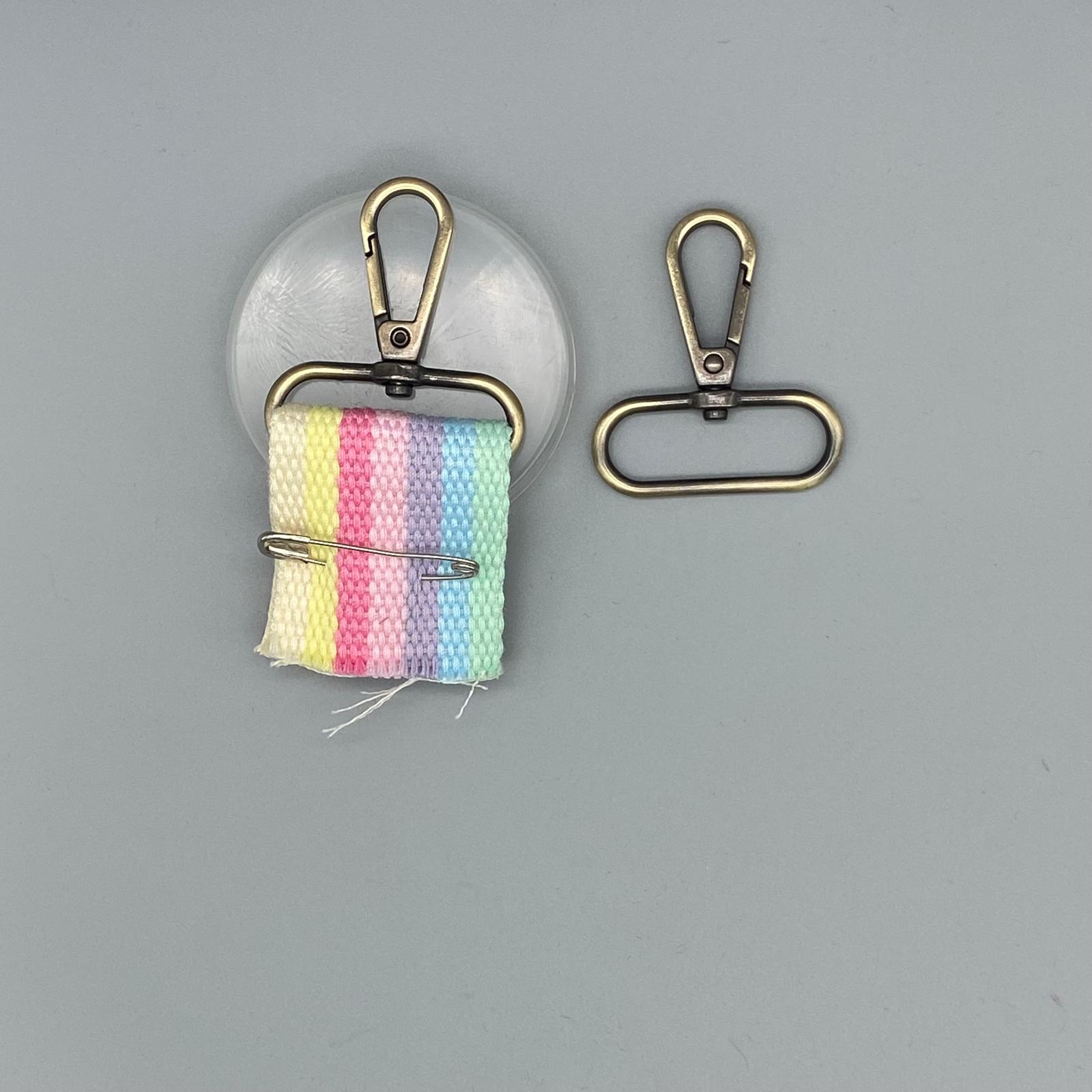 Bright pastel rainbow woven fabric scrunchie with metal clip, sewing notions on grey background.