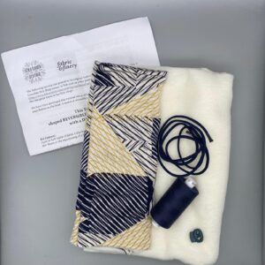 Reversible fabric kit for sewing, including patterned fabric, white fleece, navy elastic, matching thread, and sewing scissors, designed for making custom clothing and accessories.