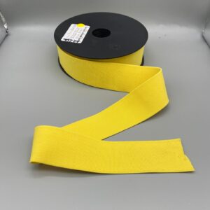 Bright yellow elastic ribbon on a grey surface, ideal for sewing, tailoring, and fashion accessories. Perfect for custom clothing and craft projects.