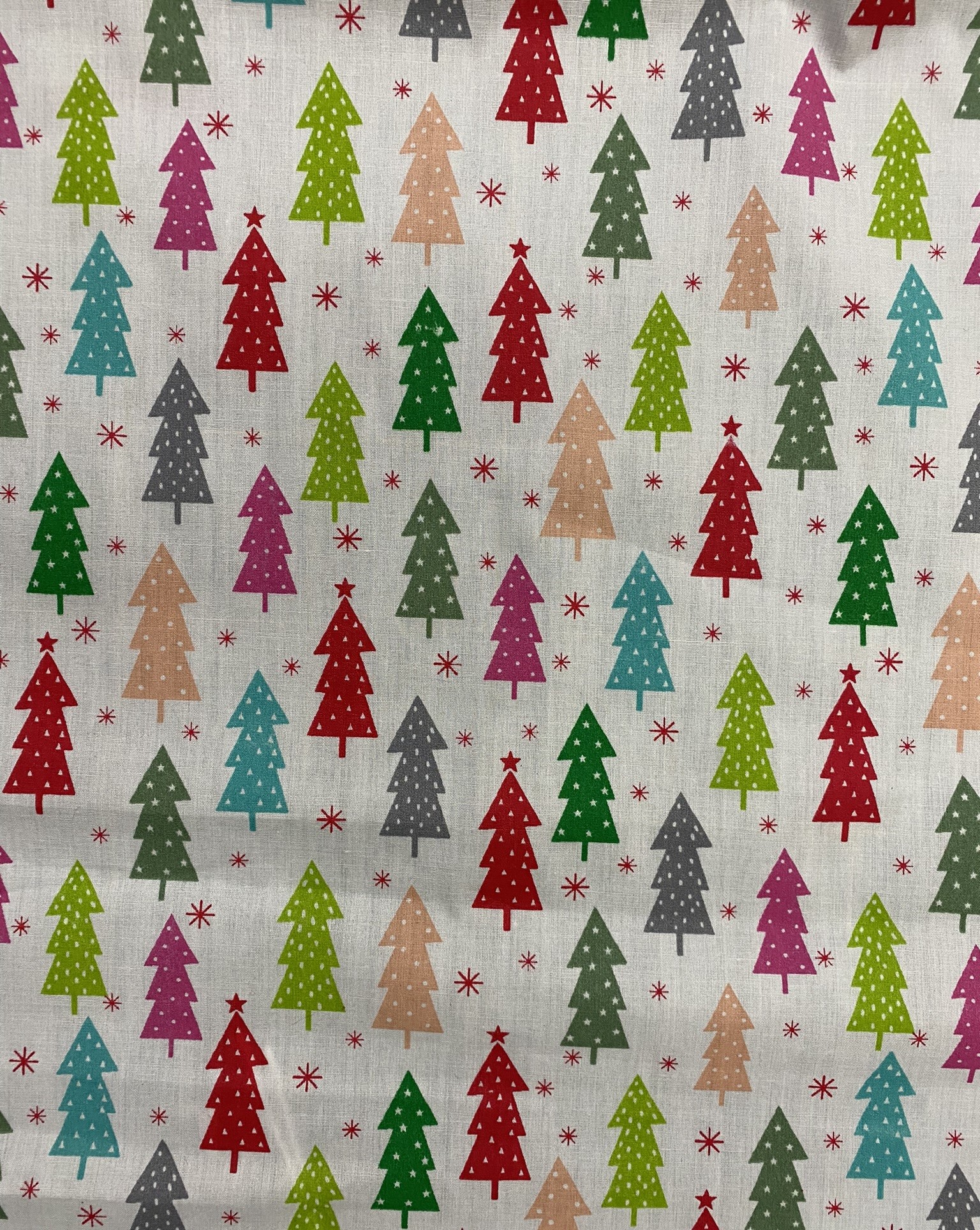 Festive Christmas tree printed fabric with colorful holiday motifs, ideal for seasonal textile projects, home decor, and gift wraps, feature vibrant red, green, pink, blue, beige, and grey trees with star accents.