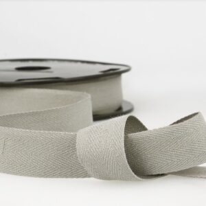 Soft beige grosgrain ribbon on spool, ideal for sewing, crafts, and gift wrapping, showcasing high-quality fabric finishing and durability for various creative projects.