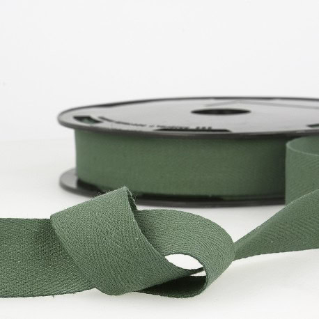 Soft green satin ribbon on a black reel, ideal for dressmaking, craft projects, and event decoration at Fabric & Finery.