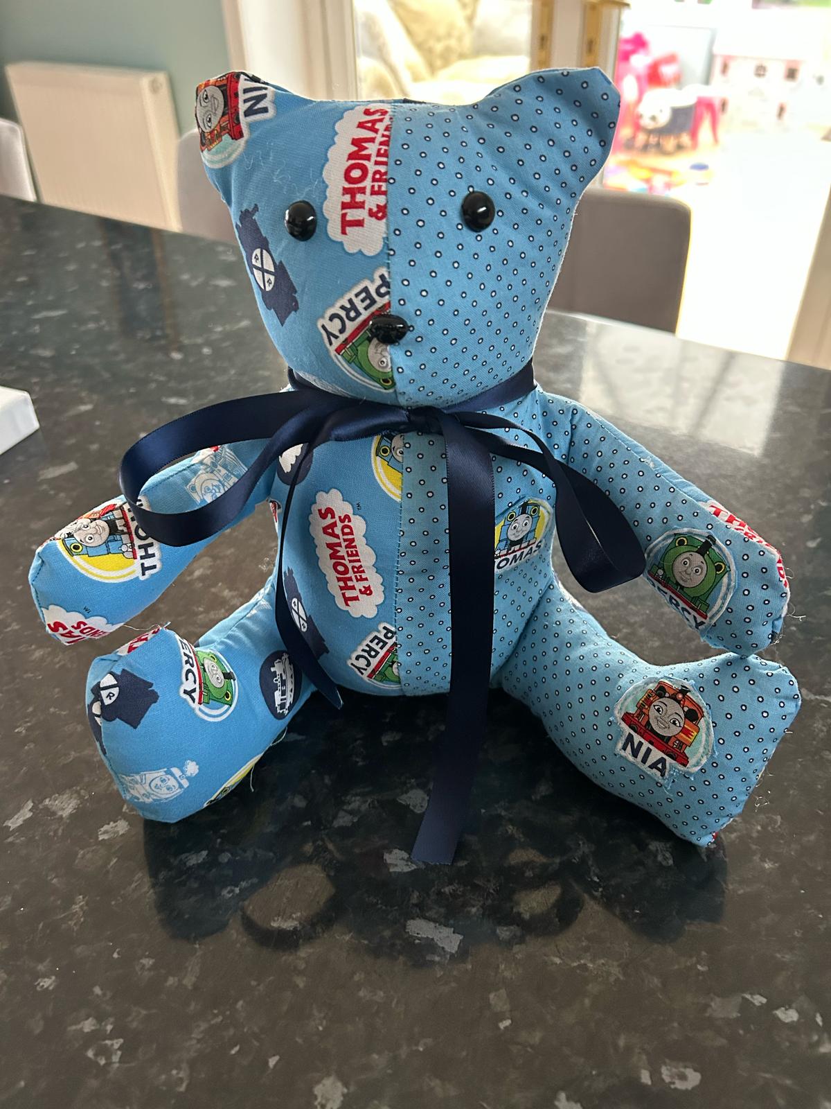 Bright blue Thomas & Friends themed fabric teddy bear with button eyes and a navy satin ribbon, featuring iconic characters and logos, perfect for children's toys or personalised gifts.