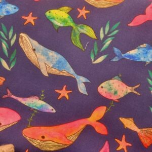 Vibrant fabric with colourful underwater sea creatures including whales, fish, starfish, and coral, perfect for ocean-themed sewing projects and children’s clothing or décor.